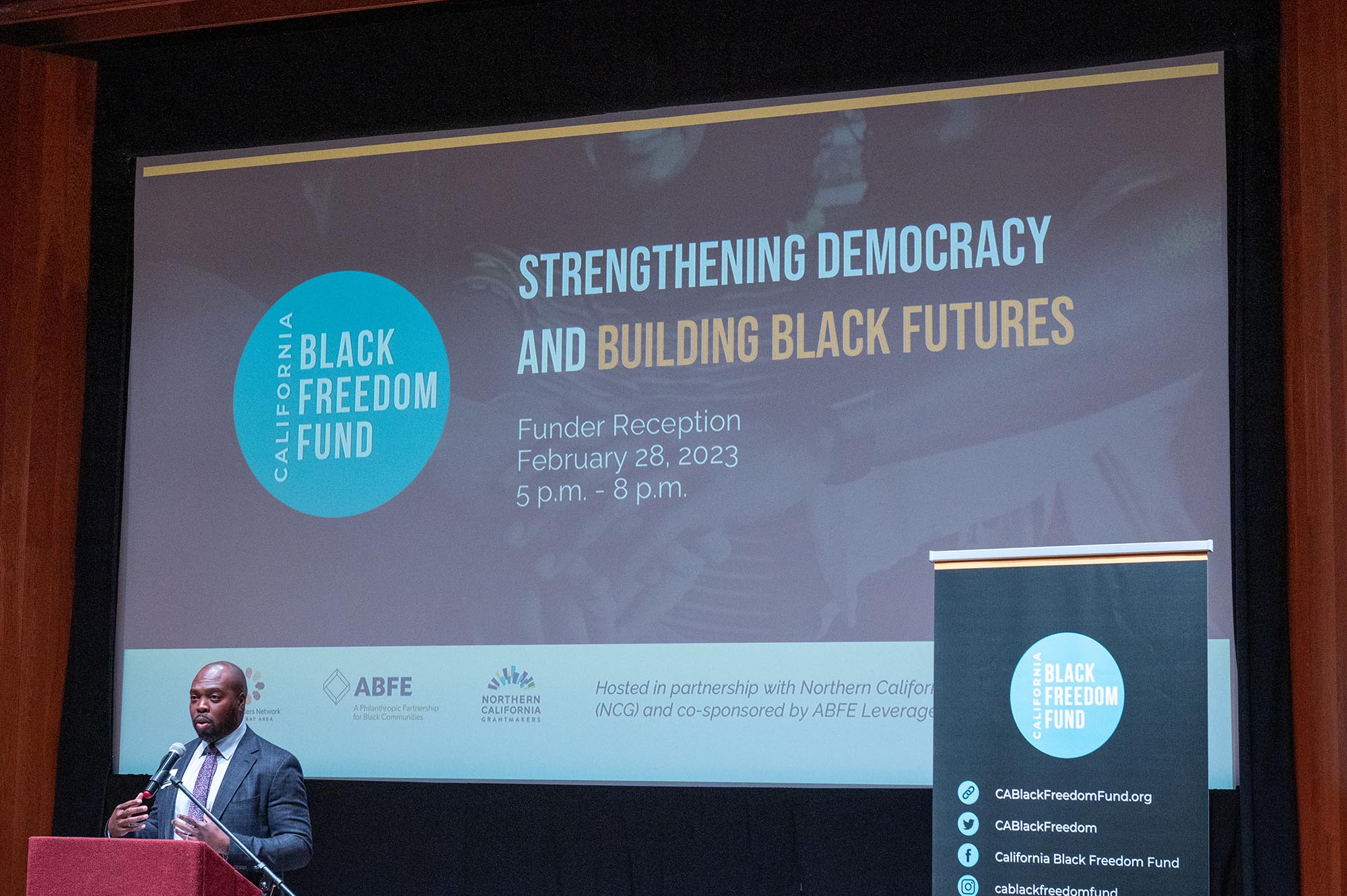 Black man speaking from podium at 2023 Black History Month Funder Reception