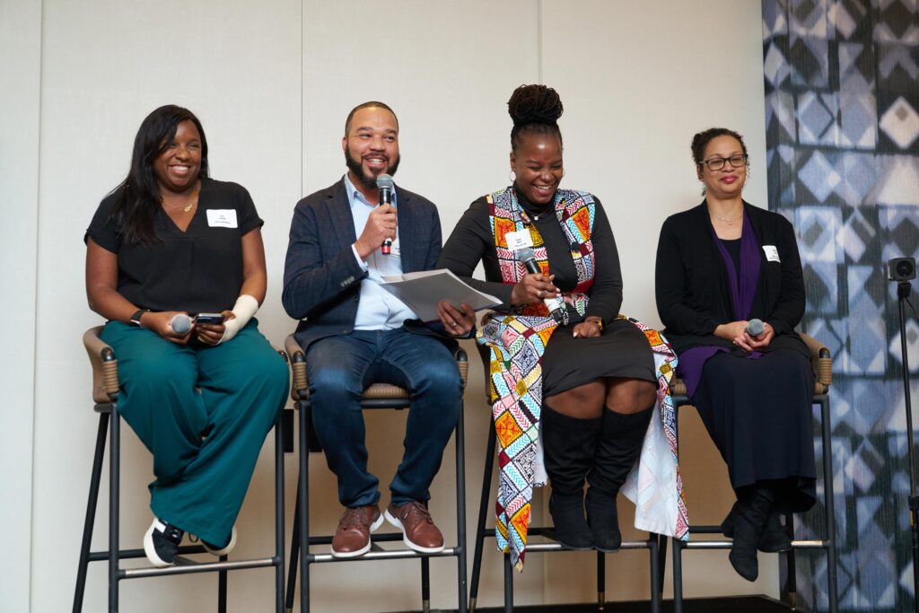 Group of four people sitting in high stools speaking into a microphone gather in Santa Monica for the first in-person convening in our Restoration Through Reparations series.