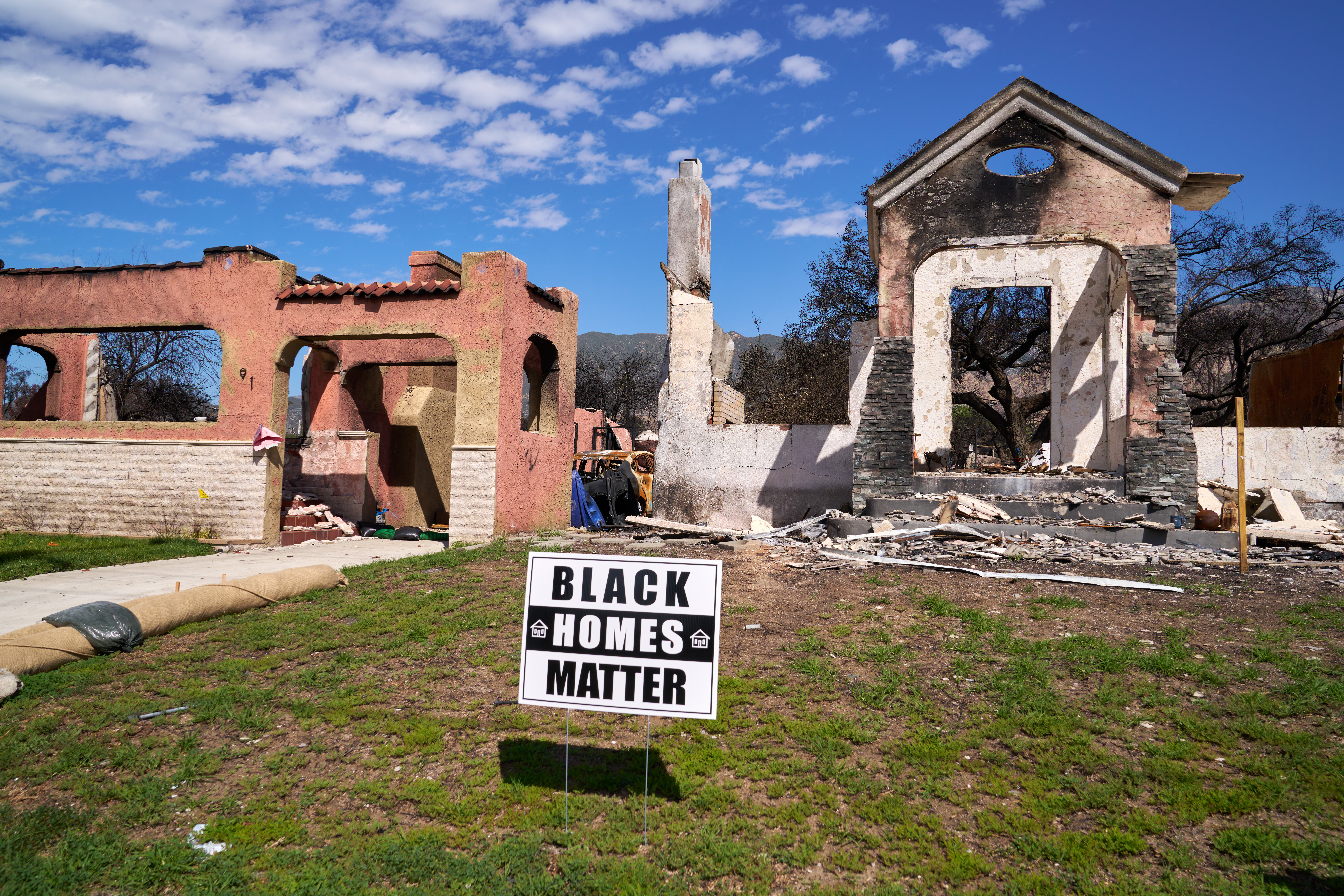 Sign in front of burned down house that reads "black homes matter"