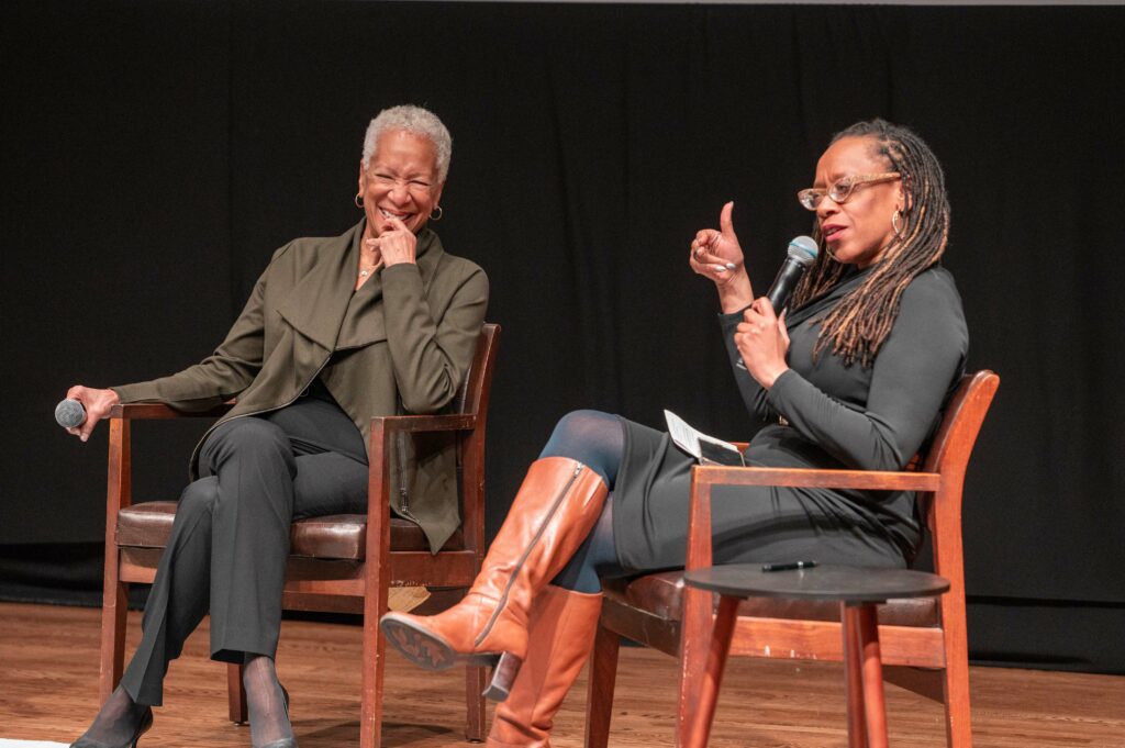 two women on stage talking and laughing