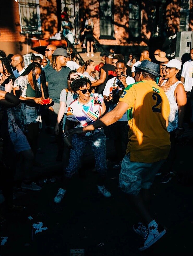 people dancing in the street with a crowd gathered around on a sunny day
