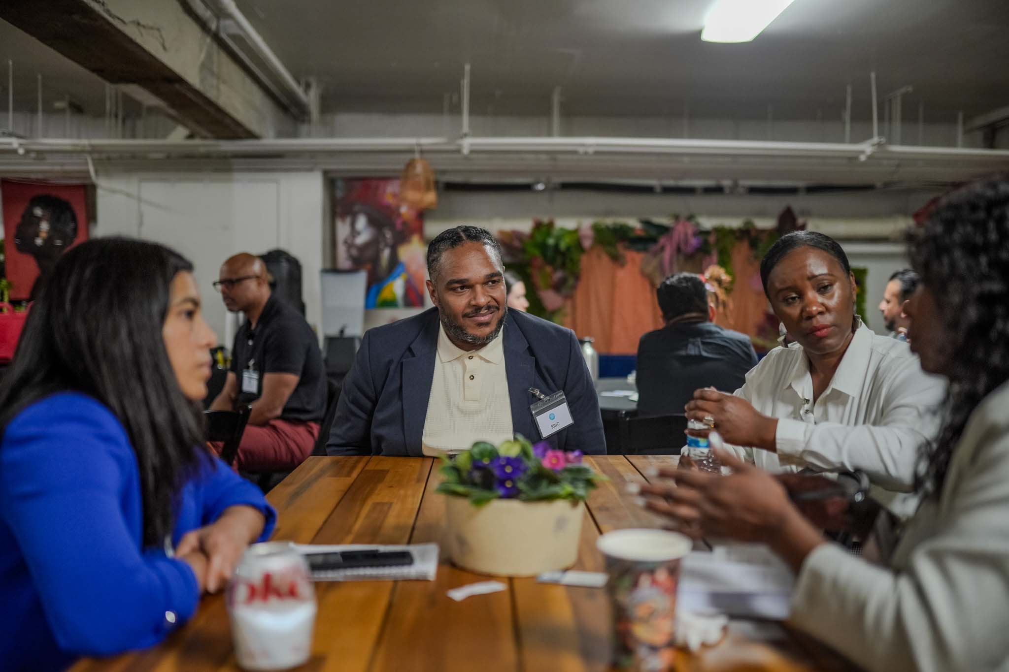 Group of people sitting around a table talking at Fresno Black Pow(Her) Building Event