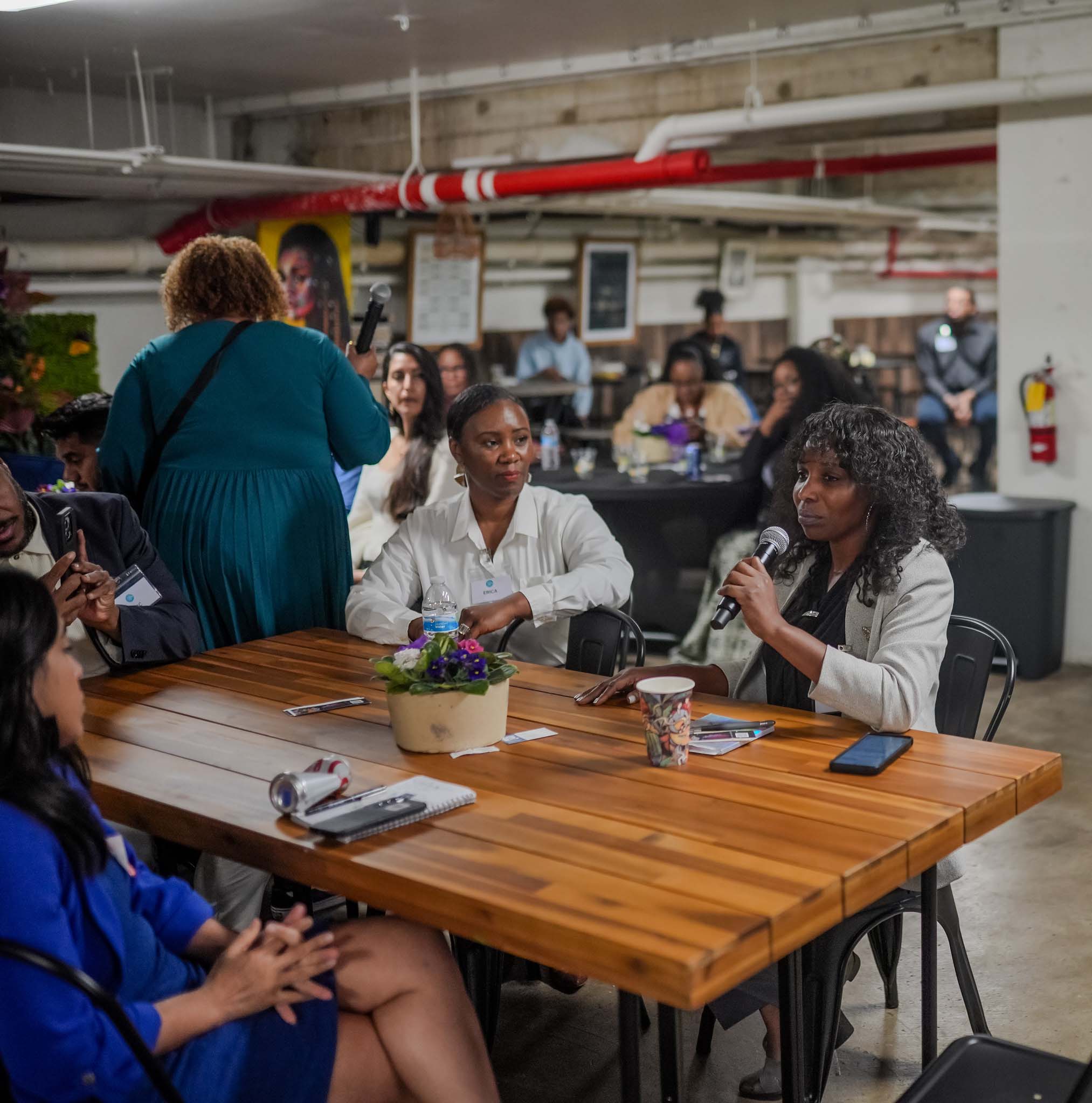 Woman sitting at a table speaking at Fresno Black Pow(Her) Building Event