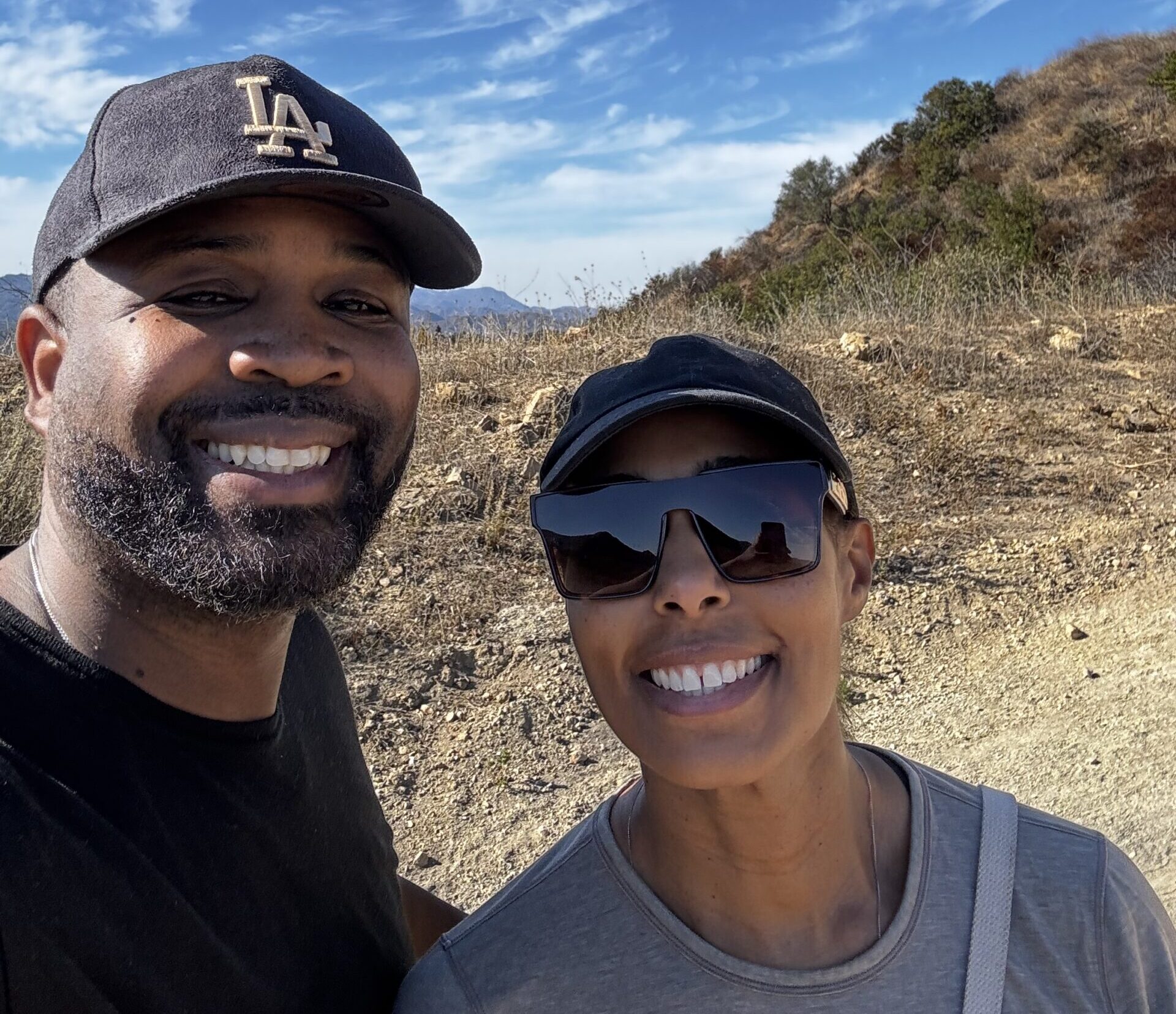 man and woman smiling for a photo while on a hike