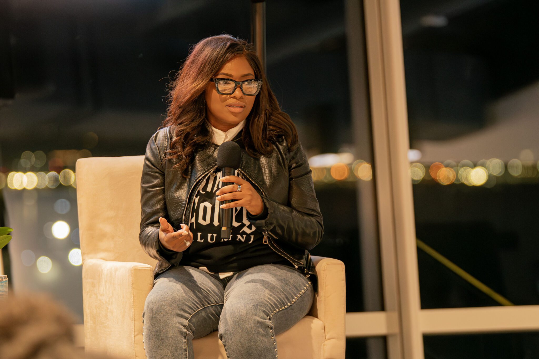 Congresswoman Jasmine Crockett seated holding a microphone and speaking to a crowd