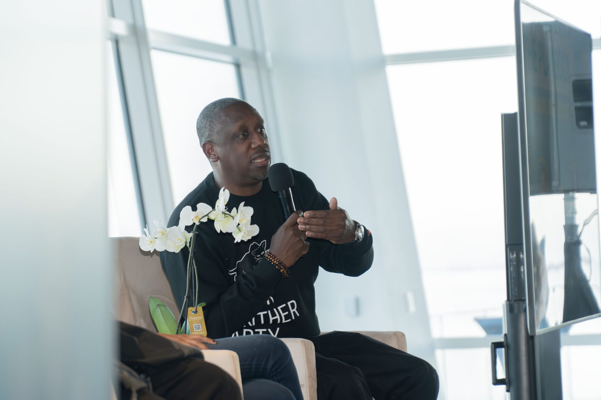 Music executive, Chaka Zulu, seated holding a microphone and speaking to a crowd