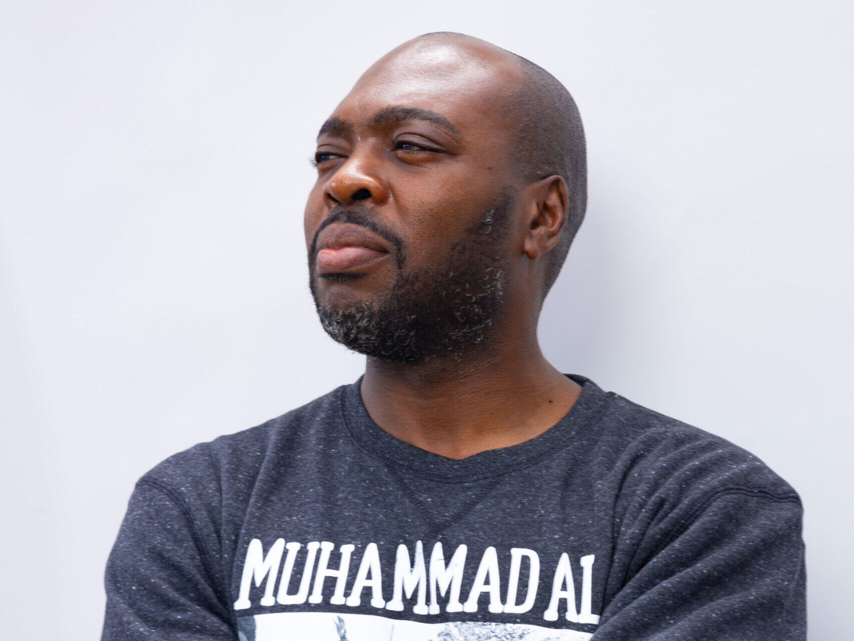Marc Philpart gazing off into the distance wearing a shirt with the name Muhammad Ali written on it