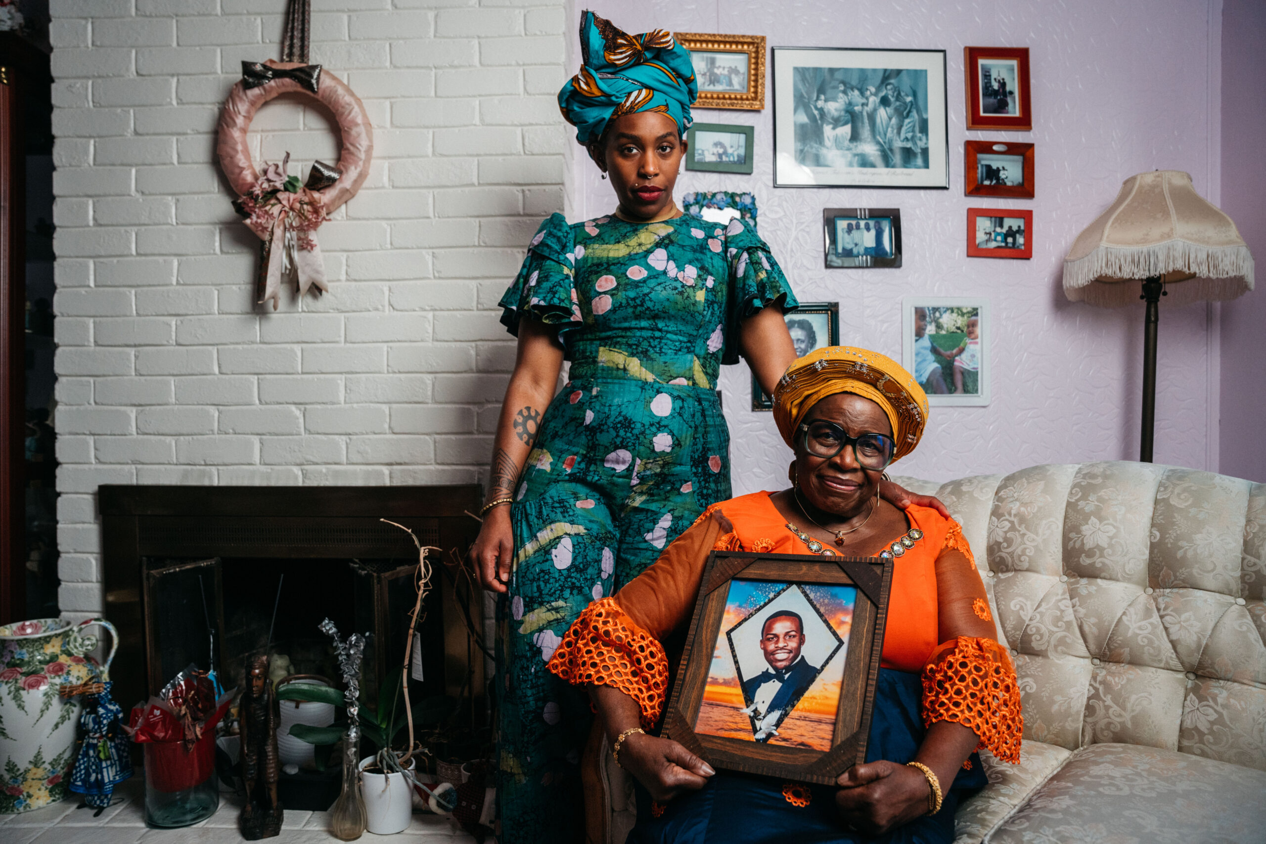 Image of Chinedu Okobi's mother and sister and mother is holding a framed picture of Chinedu.